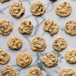 A photograph of lots of chocolate chip cookies on a marble countertop