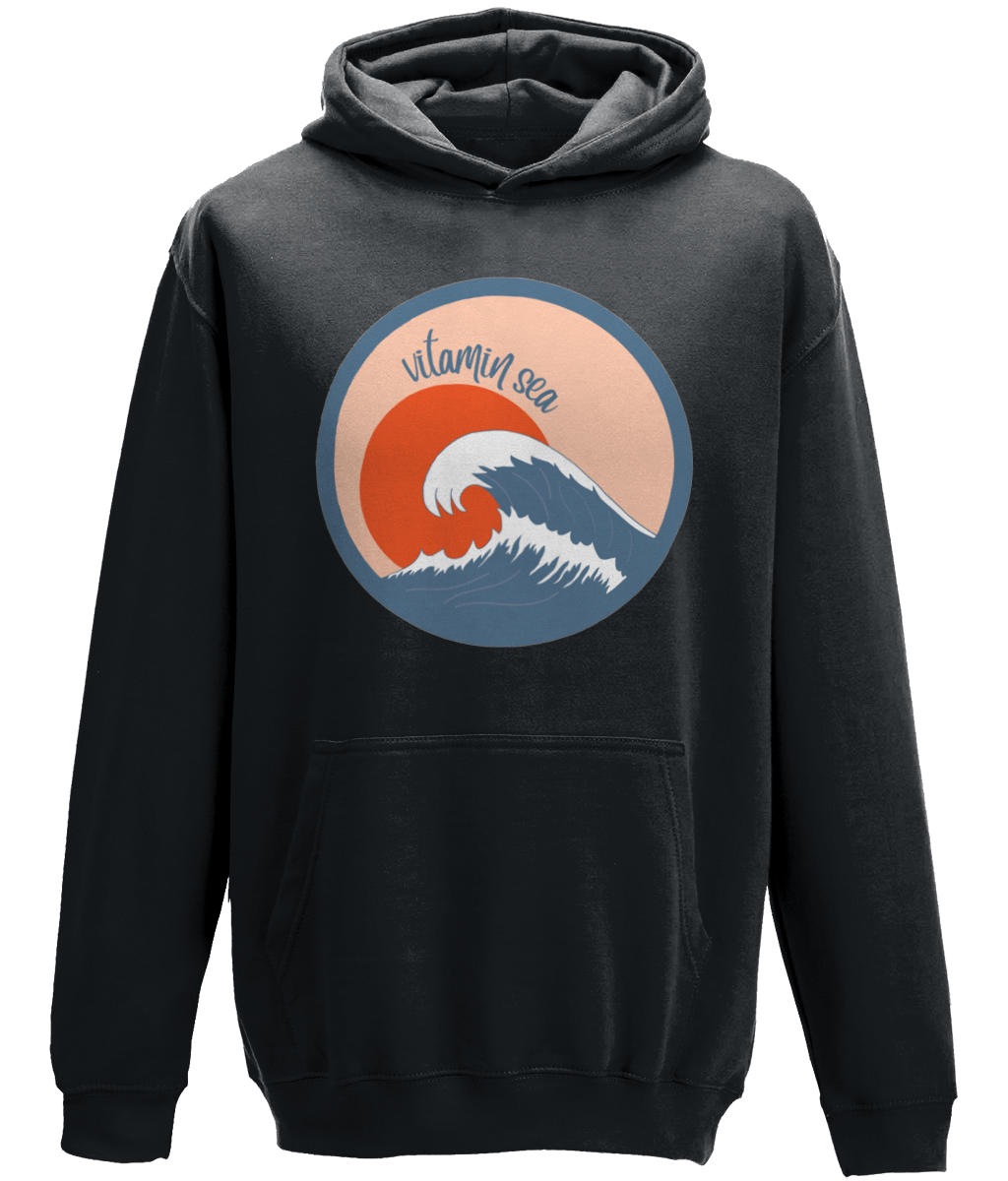 A photo of a black smoke kids hoodie with a round Vitamin Sea design featuring a large wave in front of a low orange sun