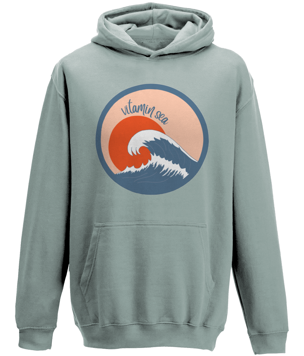 A photo of a dusty green kids hoodie with a round Vitamin Sea design featuring a large wave in front of a low orange sun
